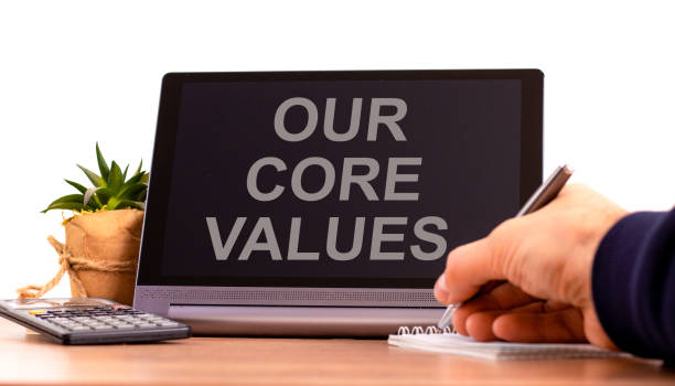 istock Our core values symbol. Tablet with words 'Our core values'. Businessman hand with pen, house plant. Beautiful white background. Business, our core values concept, copy space. 1458244830
