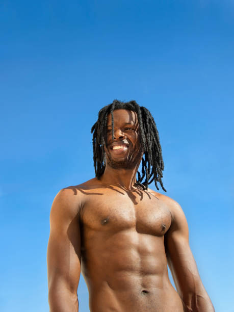 istock Handsome and muscular man with dreadlocks smiling under the sun at the beach, blue sky, sunny day 1458251237