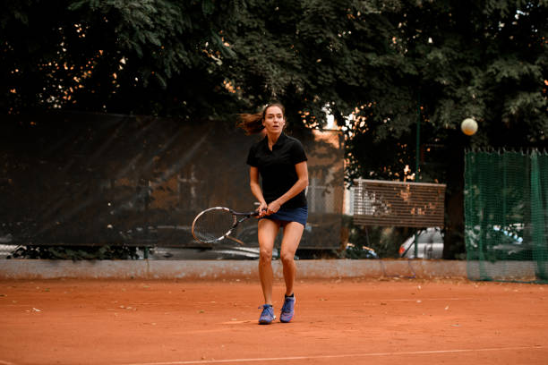 mujer tenista energética con raqueta lista para golpear una pelota de tenis. - athlete flying tennis recreational pursuit fotografías e imágenes de stock