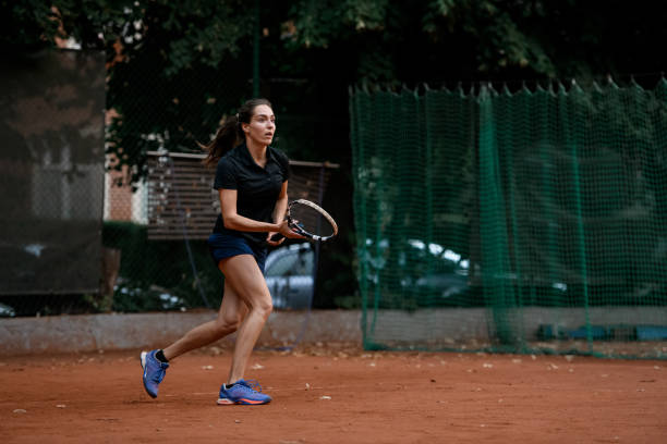 hermosa jugadora activa con raqueta de tenis jugando en la cancha de tenis al aire libre. - athlete flying tennis recreational pursuit fotografías e imágenes de stock