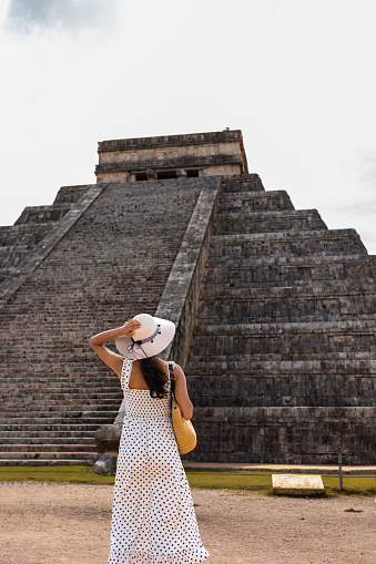 Latin woman visiting Chichen Itza pyramid in Mexico. She is enjoying beautiful view