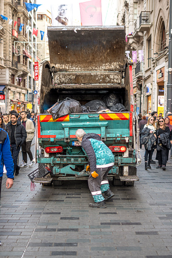 Istanbul, Turkey - January 20, 2023: Garbage truck keeping garbage on on Istiklal Avenue in Istanbul, Turkey