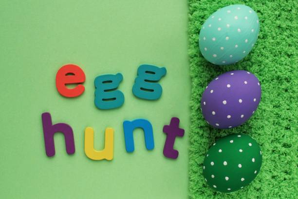 istock Egg hunt letters on green background and coloured eggs with polka dot on spring grass background 1458257470