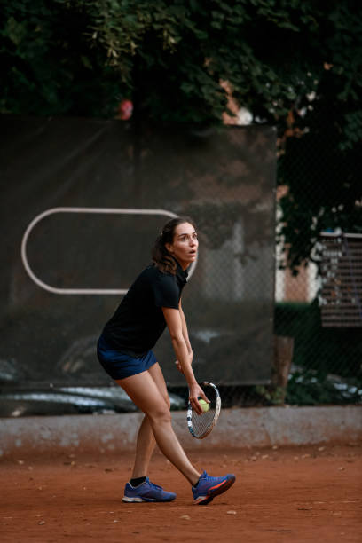 tenista activa con raqueta y pelota se prepara para servir al comienzo del juego - athlete flying tennis recreational pursuit fotografías e imágenes de stock