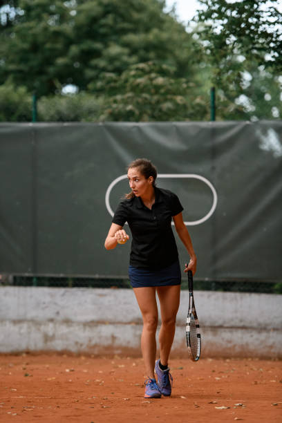 mujer sosteniendo raqueta y pelota y preparándose para servir en la cancha de tenis - athlete flying tennis recreational pursuit fotografías e imágenes de stock