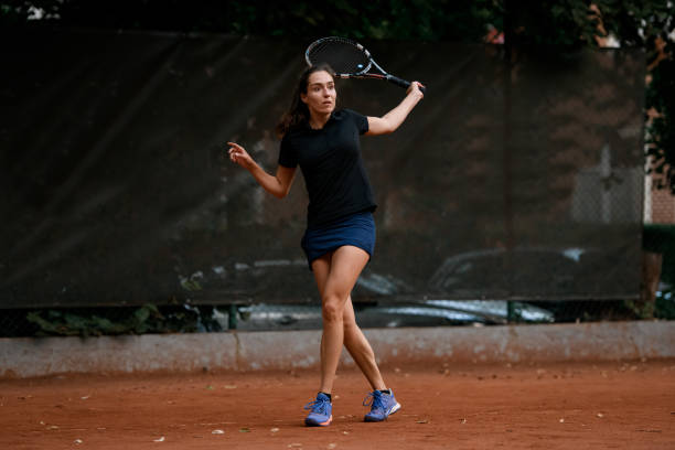 listo para golpear. hermosa tenista femenina con raqueta lista para golpear una pelota de tenis. - athlete flying tennis recreational pursuit fotografías e imágenes de stock