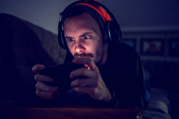istock Young gamer plays action video game on mobile phone 1458260224