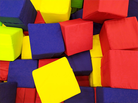 soft colored cubes in the children Is playroom. Background. Lots of soft colored cubes. Entertainment, fun, laughter. Building material, constructor. The cubes are multicolored