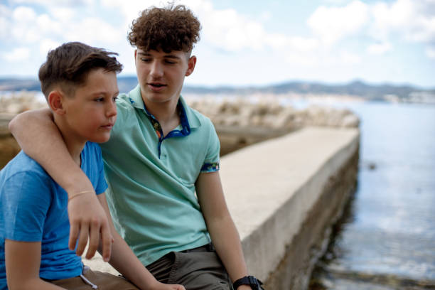 istock Brothers sitting on a rocky beach and talking 1458261579