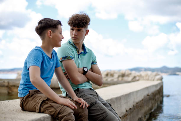 istock Brothers sitting on a rocky beach and talking 1458261598