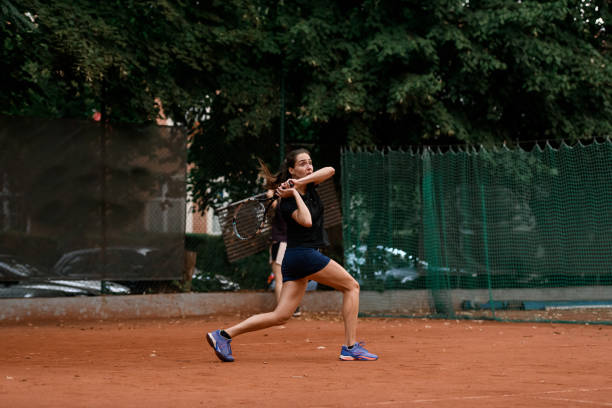 vista de la tenista deportiva con raqueta lista para golpear la pelota de tenis volando hacia ella. - athlete flying tennis recreational pursuit fotografías e imágenes de stock