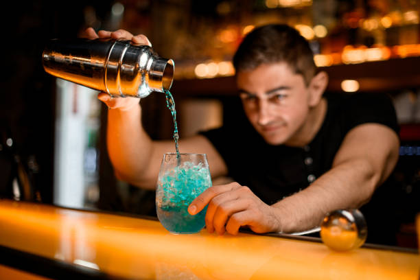 istock view of glass with ice into which bartender accurate pours blue cocktail from shaker 1458262774