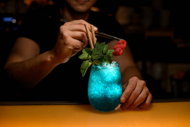 istock close-up view on glass with blue cocktail with ice and green mint which bartender decorates with raspberries 1458263405