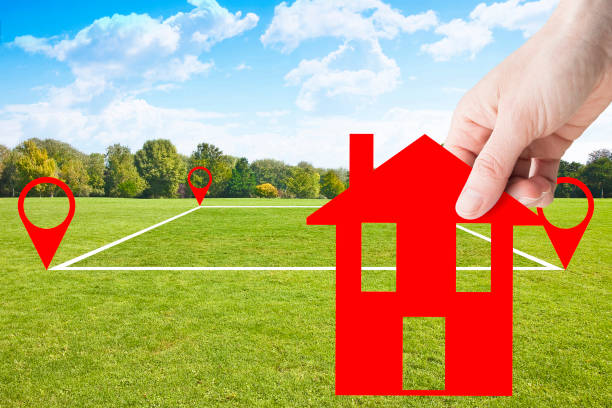 istock Land plot management - real estate concept with a vacant land parcel available for building construction - housing concept with hand holding a little red house in a residential area for sale 1458263734