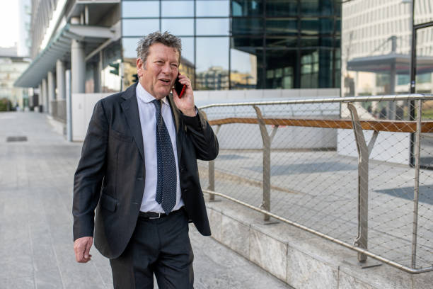 istock Businessman using mobile phone walking in the city 1458268406