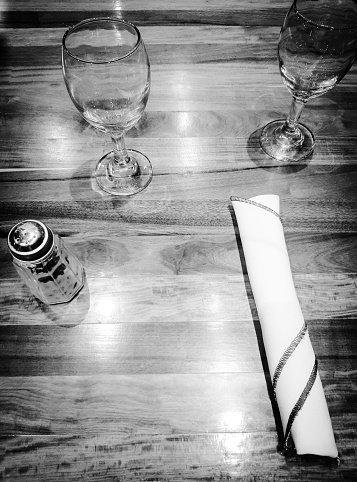 Table setting for dinner:  Napkin,  salt and two glasses on wooden table. Copy space