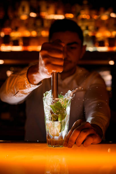 istock Hand of male bartender press ingredients for mojito using muddler. Close-up 1458270046