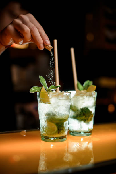 istock hands of bartender pour sugar into glass with mojito on the bar 1458270341