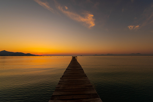 Wooden pier on the beach. Wooden bridge on the beach. Sunrise on the beach, golden hour. Majorca island, 