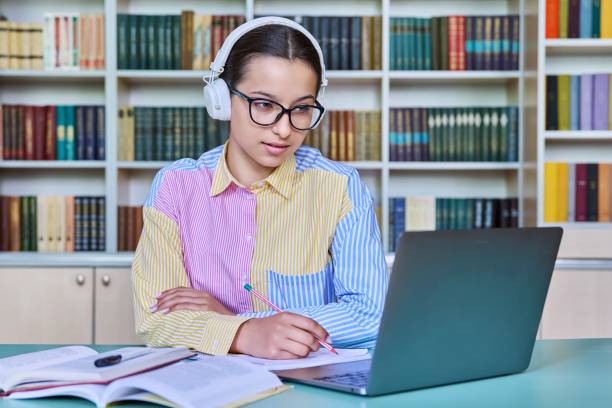istock Teenage girl student studying in library, using laptop 1458273979
