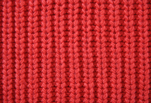 Red knitted texture, soft sweater background. Christmas backdrop. Winter blank.