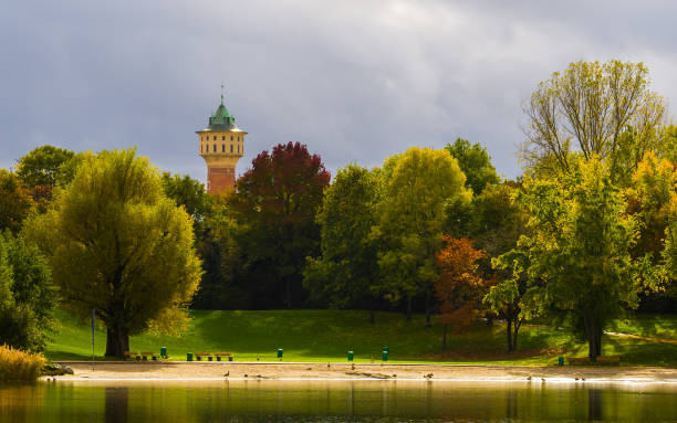 istock Sunlit landscape at lake with trees and watertower 1458282589