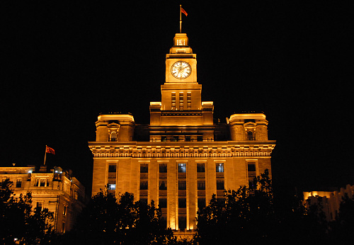The Custom House on the Bund in Shanghai, China at night. The Bund is a riverfront area in central Shanghai with many historical concession era buildings.