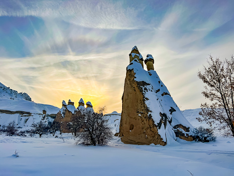 Volcanic rock formation in Cappadocia, Central Anatolia, Turkey. Historical area covered with snow. Beautiful fairy tale like winter landscape with rock hoodoos. Panorama of unique geological fairy Chimneys under snowfall