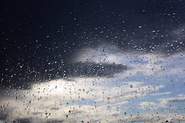 istock Raindrops on window glass on blurred background of sky with storm clouds 1458287495