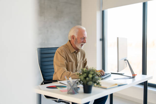 istock Focused older senior businessman typing on computer keyboard, writing an e-mail, working online 1458289696