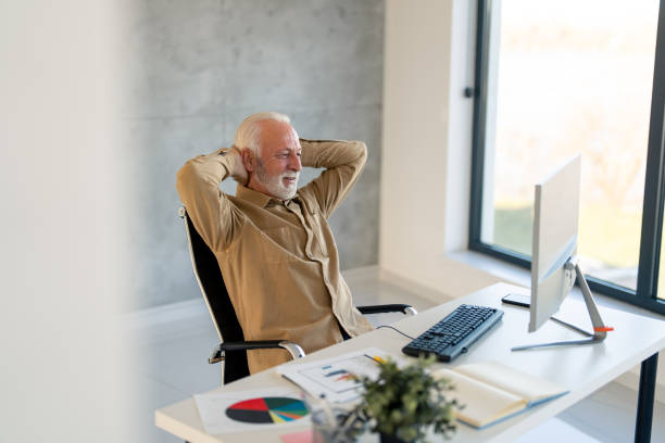 istock Satisfied grey haired entrepreneur relaxing after successful work sitting with hands behind his head 1458289708