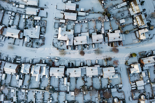 Wide angle top down aerial view of a typical UK housing estate covered in winter snow. Staffordshire, England, UK.