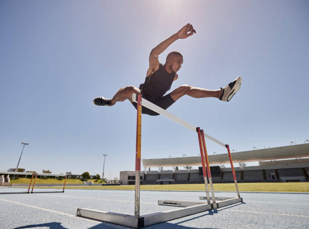 istock Running, jump and athlete hurdle for a speed exercise, marathon or runner training in a stadium. Short health, cardio and man run fast for a jumping competition or fitness workout for sports wellness 1458296907