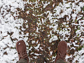 Feet in boots on grass covered with snow.