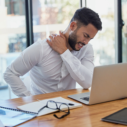 Man, shoulder pain and laptop while working in office suffering from stress, depression and burnout at desk. Arab businessman sitting to massage body feeling tired and fatigue