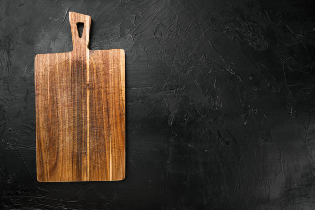 istock Bamboo kitchen cutting board empty for empty for copy space for text or food, top view flat lay , on black dark stone table background 1458304402