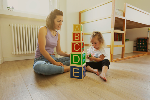 Child playing with colorful toy blocks. Little boy building tower at home or day care. Educational toys for young children. Construction block for baby or toddler kid.