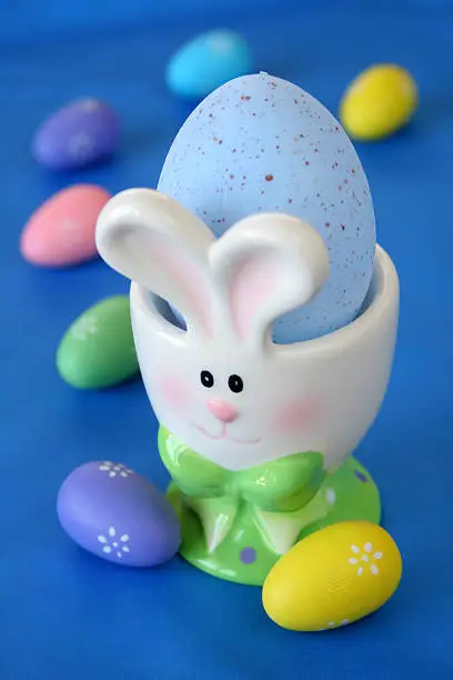 a bunny easter egg holder with an easter egg of blue on a blue background.