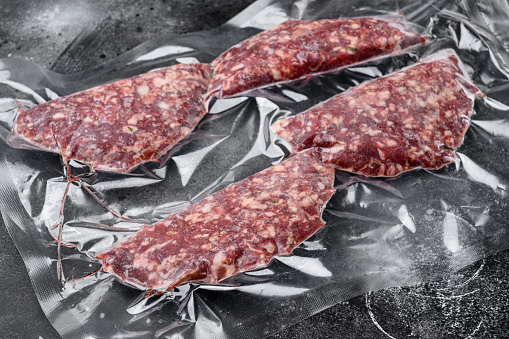 Beef veal cutlets in vacuum plastic pack set, on black dark stone table background