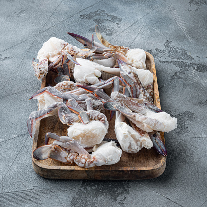 Fresh raw flower crab or blue crab frozen parts set, on wooden tray, on gray background