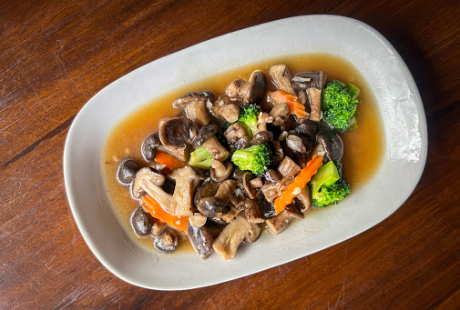stir fried mushroom with broccoli carrot vegetable, shiitake mushrooms with oyster sauce cooking food on white plate, shiitake mushroom cooked by frying
