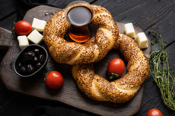 istock Bagel Simit with sesame traditional pastry with breakfast ingredients olive and tomato cheese, on black wooden table background 1458329204