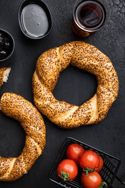 istock Traditional middle eastern sesame ring cookies kandil simidi bagel with breakfast ingredients olive and tomato cheese, on black dark stone table background, top view flat lay 1458330500