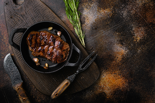 Fresh juicy delicious beef steak, on old dark rustic table background, top view flat lay.