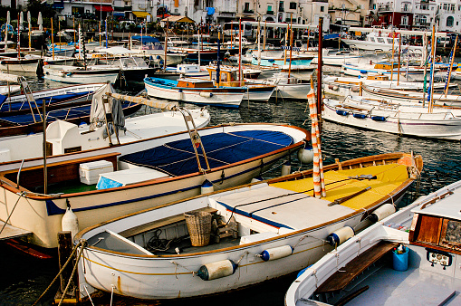 Various collection of small boat are moored and waiting in the harbor marina of Capri, Italy.