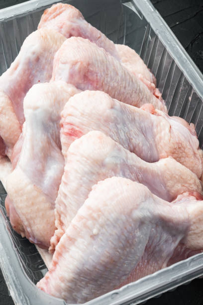 istock Raw chicken wings in plastic pack, on black stone background 1458337111