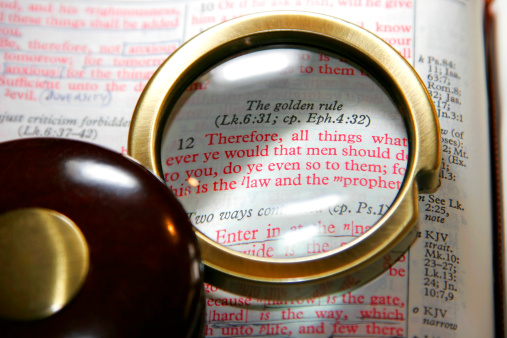 A vintage pocket magnifying glass highlights the Golden Rule text of the Holy Bible in the book of Matthew, Chapter 7 - king James Version (shallow focus).