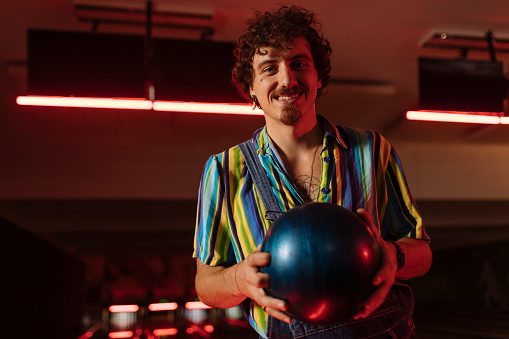 A cheerful man holds a bowling ball before the match