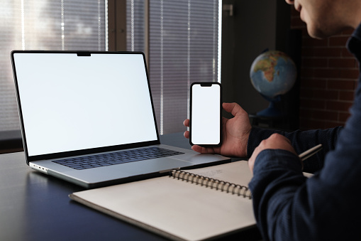 Blank screen desktop computer and laptop on wooden table with blur office background, Mock up for display or montage, 3D rendering.