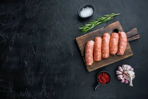 Traditional pork sausages, flat lay with space for text, on black background.